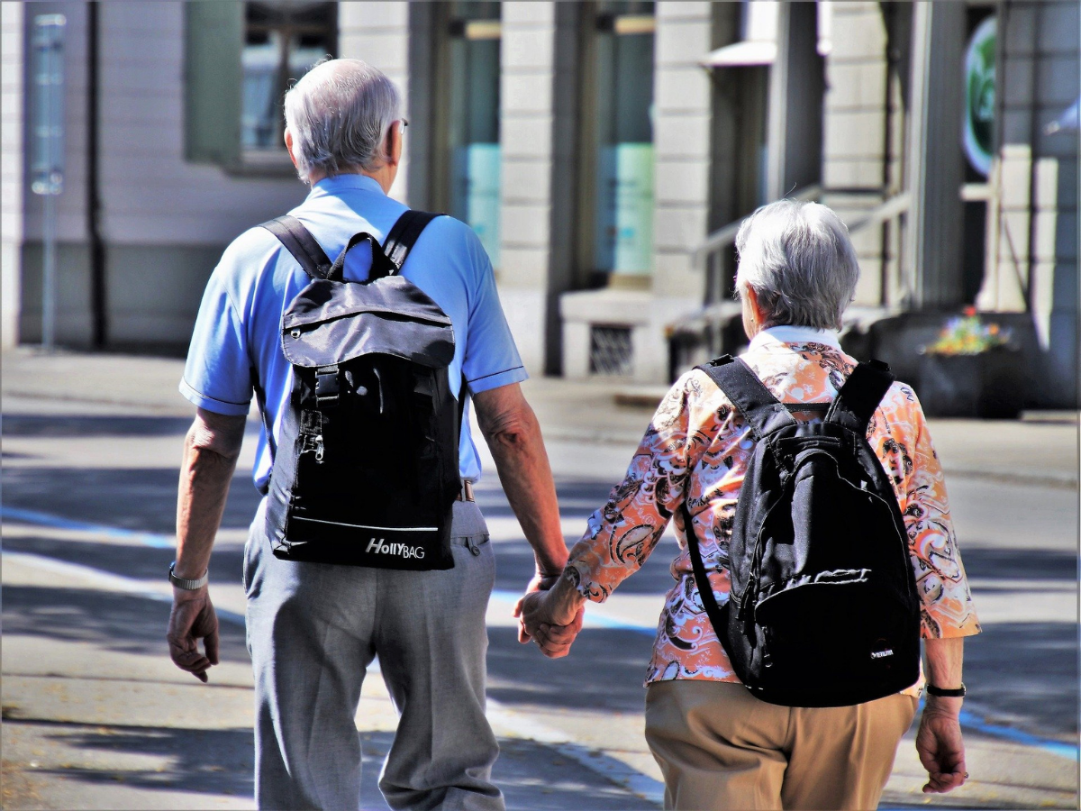 Two older people holding hands while walking to show how important it is to keep seniors involved during the holidays