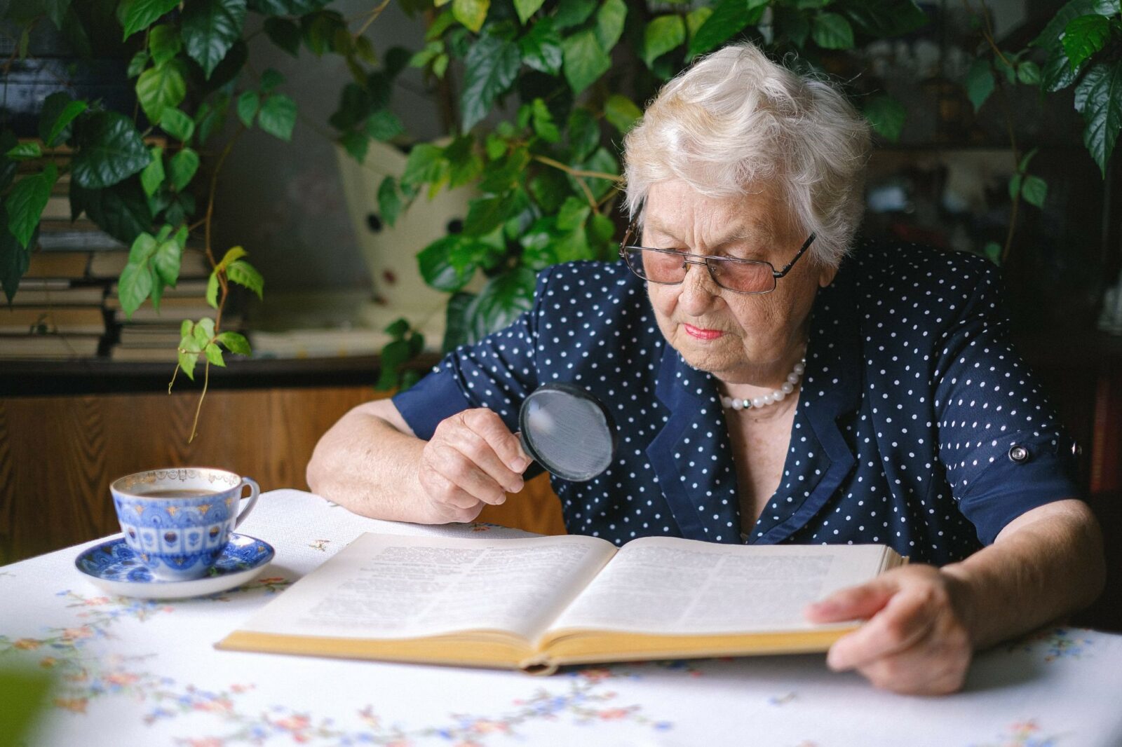 A woman using a seeing eye glass as she reads to demonstrate the importance of healthy vision