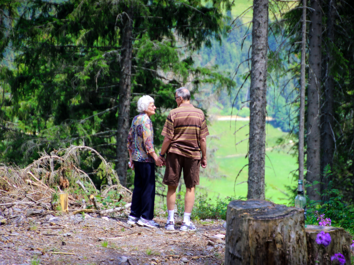 Two older people standing together on the edge of the woods to show the importance of keeping seniors active