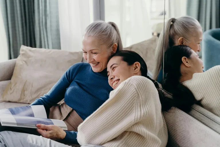 elderly lady reading a book with a young woman hugging her