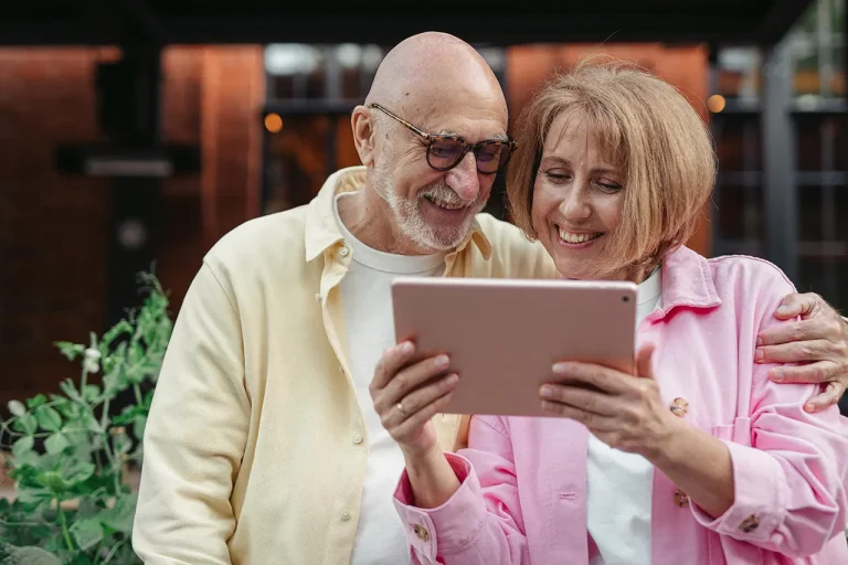 elderly man looking at a tablet with his daughter