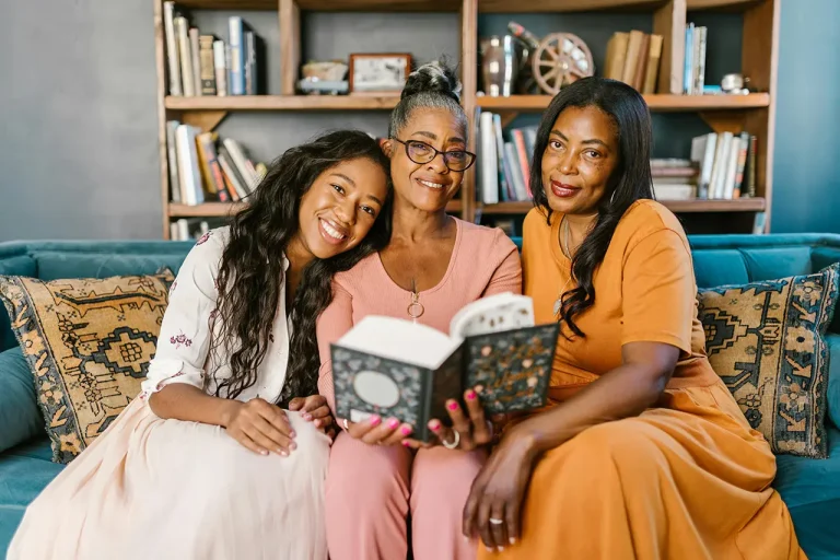 grandmother, daughter, and granddaughter reading a book together