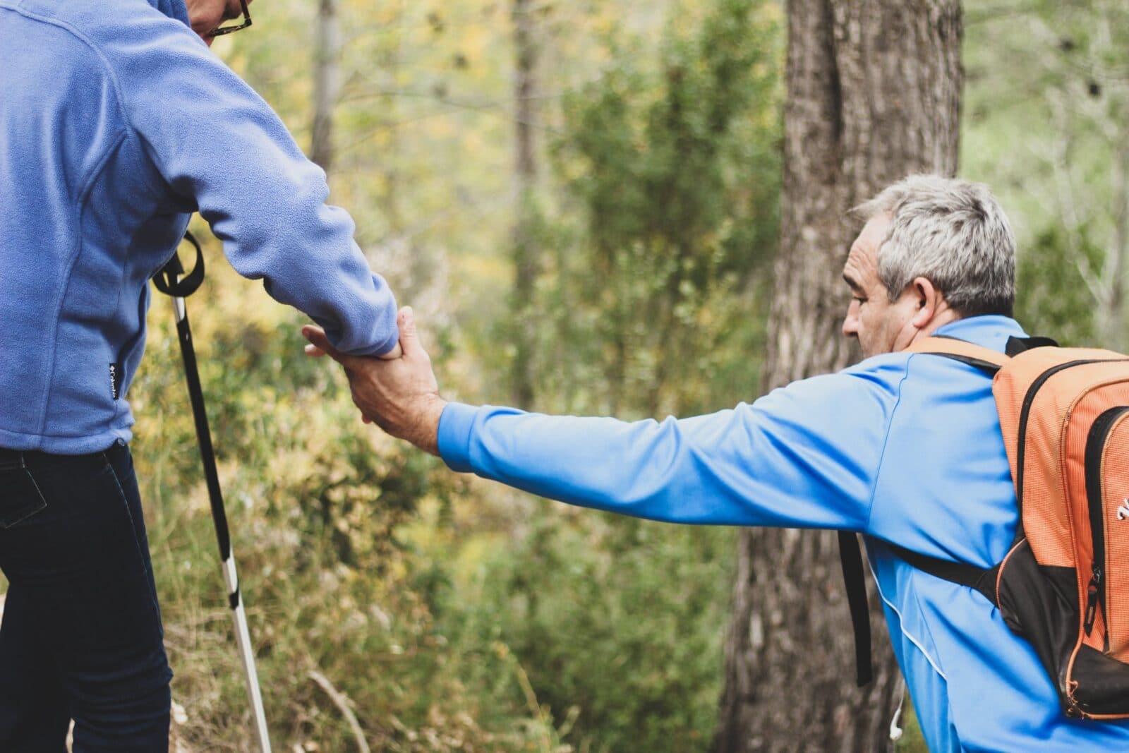 man helping another man hike