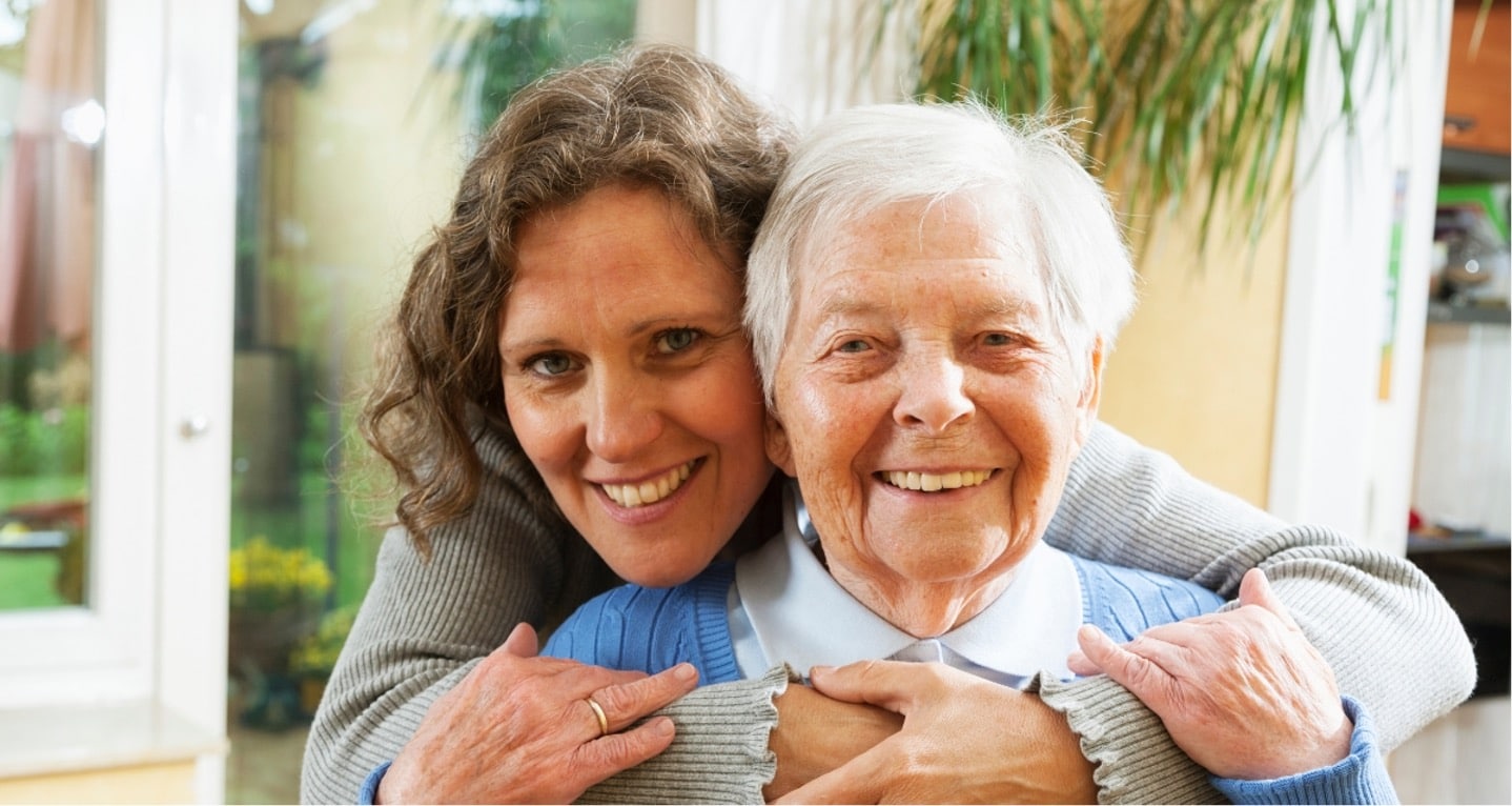 woman hugging senior and smiling